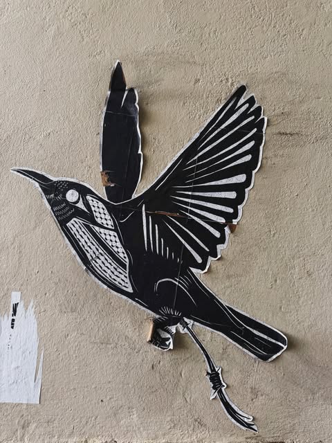 Black-and-white bird artwork installed on a city wall